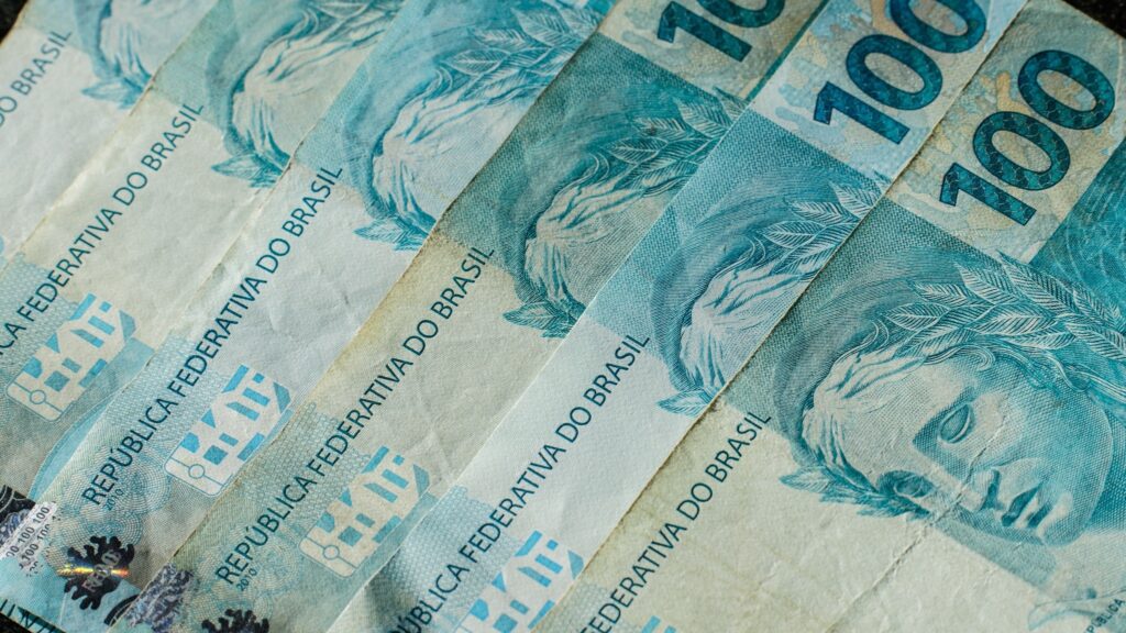 Cédulas de 100 reais do Brasil sobrepostas em close-up.