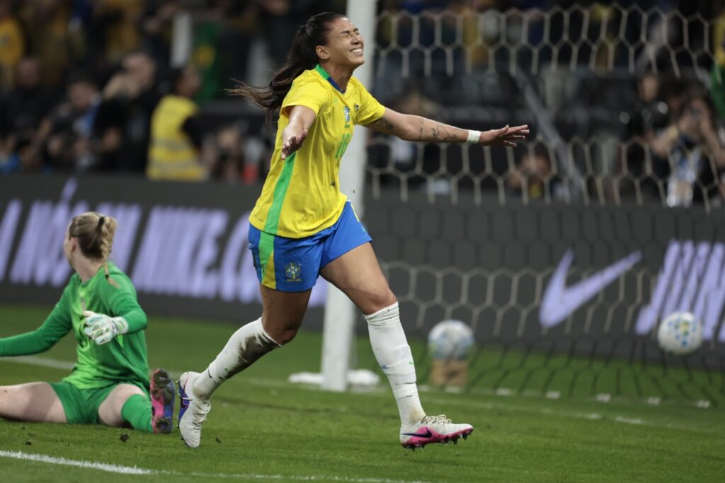 Jogadora da Seleção Brasileira Feminina com os braços abertos comemora gol em jogo contra os Estados Unidos.