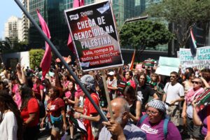 Manifestantes em ato político seguram cartaz com os dizeres "CHEGA DE GENOCÍDIO NA PALESTINA Lula, rompa já todas as relações com Israel".