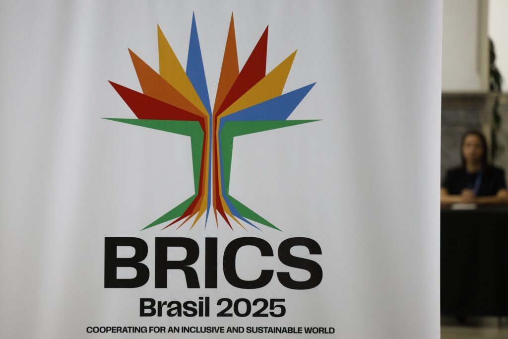 Banner branco com o logotipo colorido do BRICS, os dizeres "BRICS Brasil 2025" e a frase "COOPERATING FOR AN INCLUSIVE AND SUSTAINABLE WORLD".