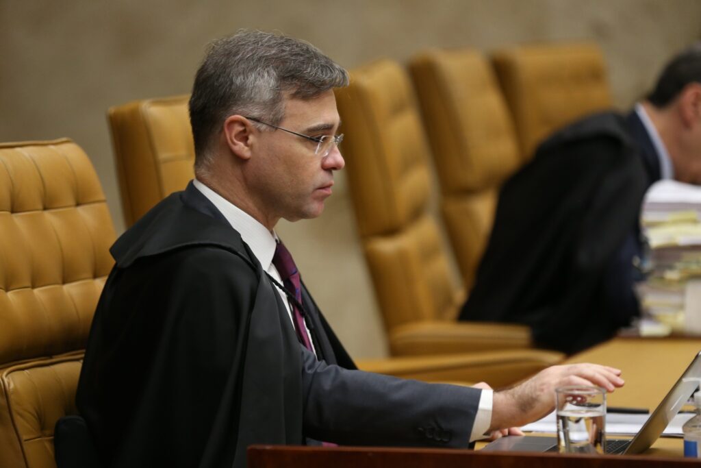 Ministro André Mendonça, trajando toga preta, sentado em poltrona de couro durante sessão no Supremo Tribunal Federal.