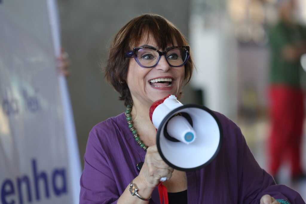 Mara Régia sorri enquanto fala ao megafone.