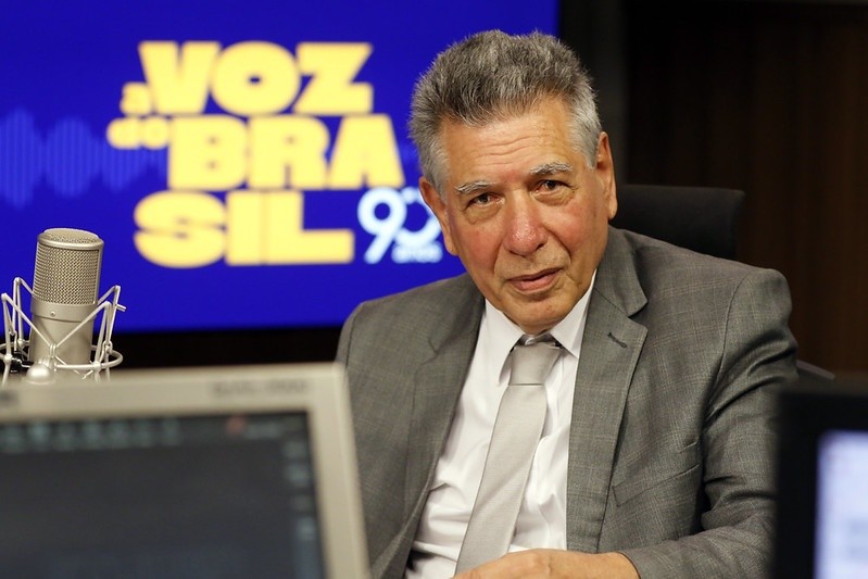 Luiz Antônio Elias, presidente da FINEP, em estúdio diante de tela com os dizeres "A Voz do Brasil 93 anos".