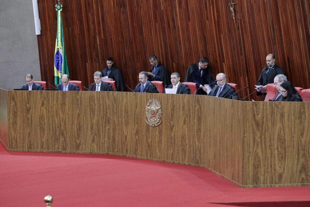 Mesa principal do plenário do Tribunal Superior Eleitoral com autoridades sentadas.