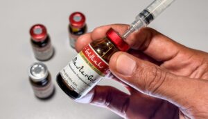 Mão segura frasco de esteroides "Master Gold" enquanto extrai o líquido com uma seringa.