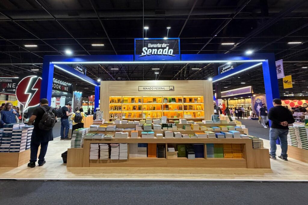 Estande da "Livraria do Senado" em feira de livros, com obras expostas em prateleiras de madeira e placas com os dizeres "livraria do Senado" e "SENADO FEDERAL".