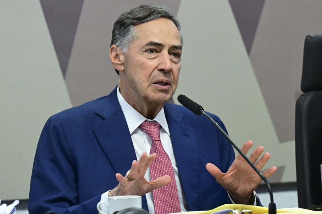 Luís Roberto Barroso gesticula ao falar ao microfone em seminário sobre direito tributário.