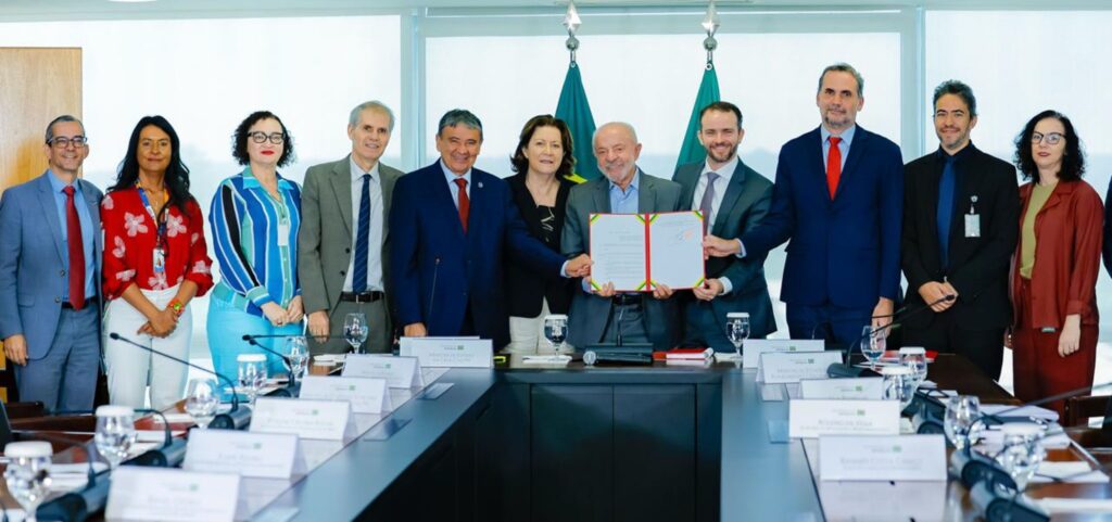O presidente Luiz Inácio Lula da Silva e autoridades posam segurando documento durante anúncio no Palácio do Planalto.