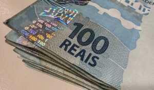 banco central: maço de cédulas de cem reais sobre uma superfície clara.