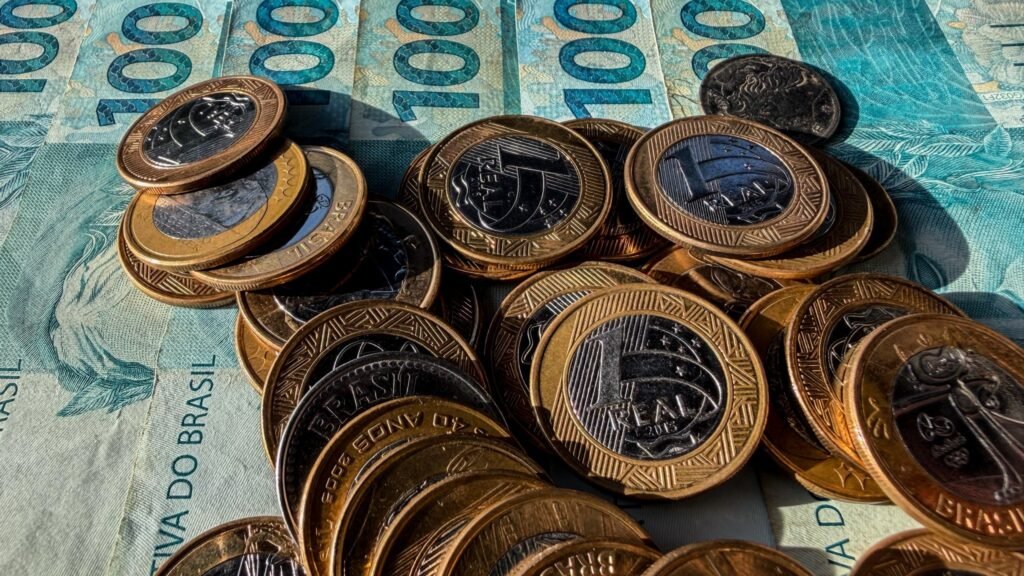 acordo Casas Bahia: moedas de um real empilhadas sobre cédulas de cem reais.
