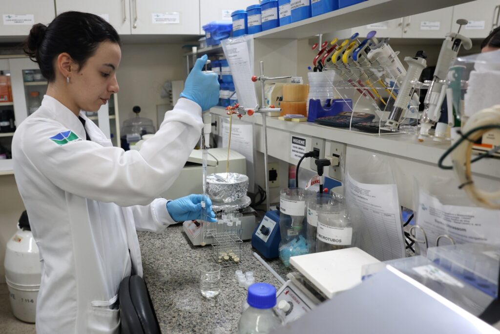 imunidade tributária: Pesquisadora com jaleco branco manipula substância em laboratório científico da Embrapa.