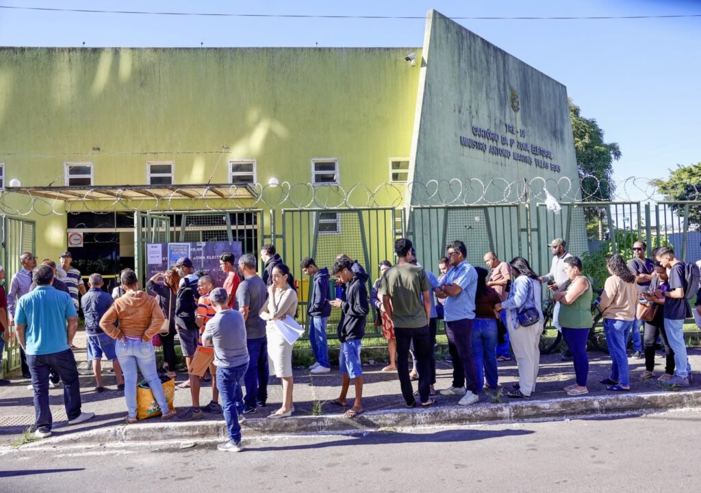 Pessoas em fila em frente ao cartório eleitoral para regularização e consulta ao local de votação.