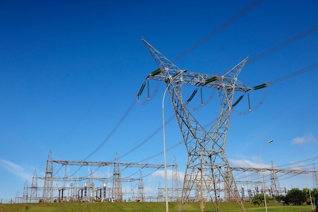 leilao da aneel: Torres de alta tensão e subestação de energia elétrica sob céu azul.