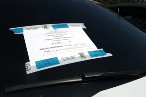 crimes eleitorais: Detalhe de para-brisa de carro preto com documento oficial da Polícia Federal fixado.