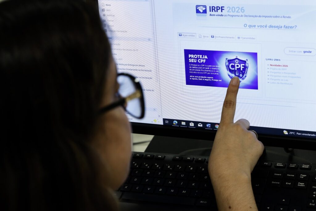 restituições do imposto de renda: pessoa aponta para tela de computador com interface do programa IRPF 2026.