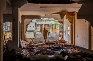 cota de alerta: Militar fardado caminha por entre escombros e lama no interior de um prédio destruído.
