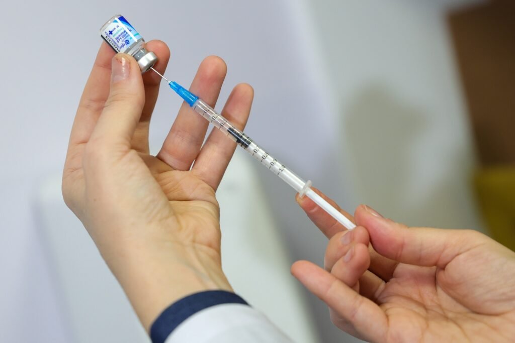 vacinacao de gestantes: profissional de saúde prepara dose de vacina com frasco e seringa.