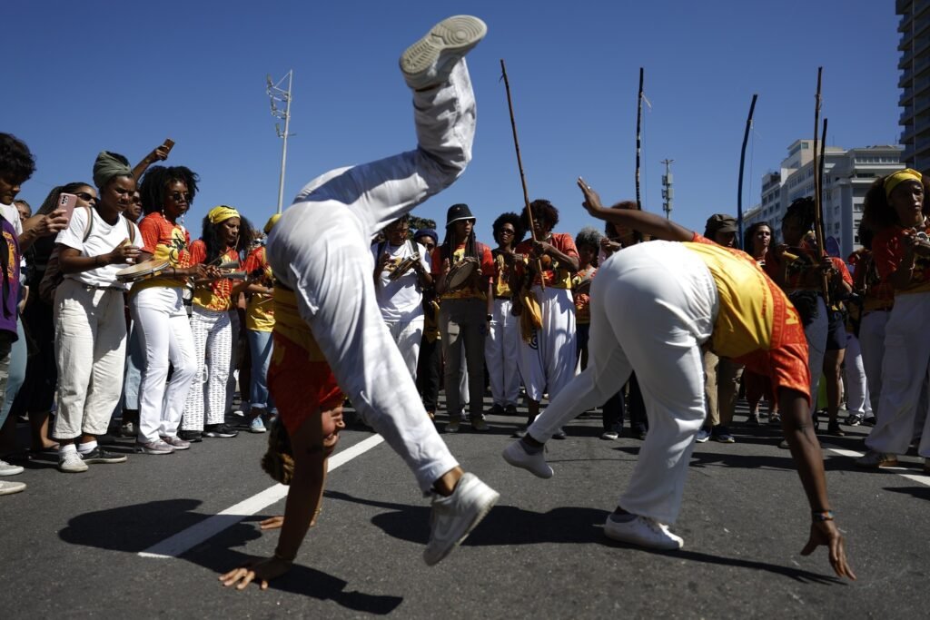 Operação Contenção: Duas mulheres participam de manifestação com movimentos de capoeira na rua durante ato público no Rio de Janeiro.