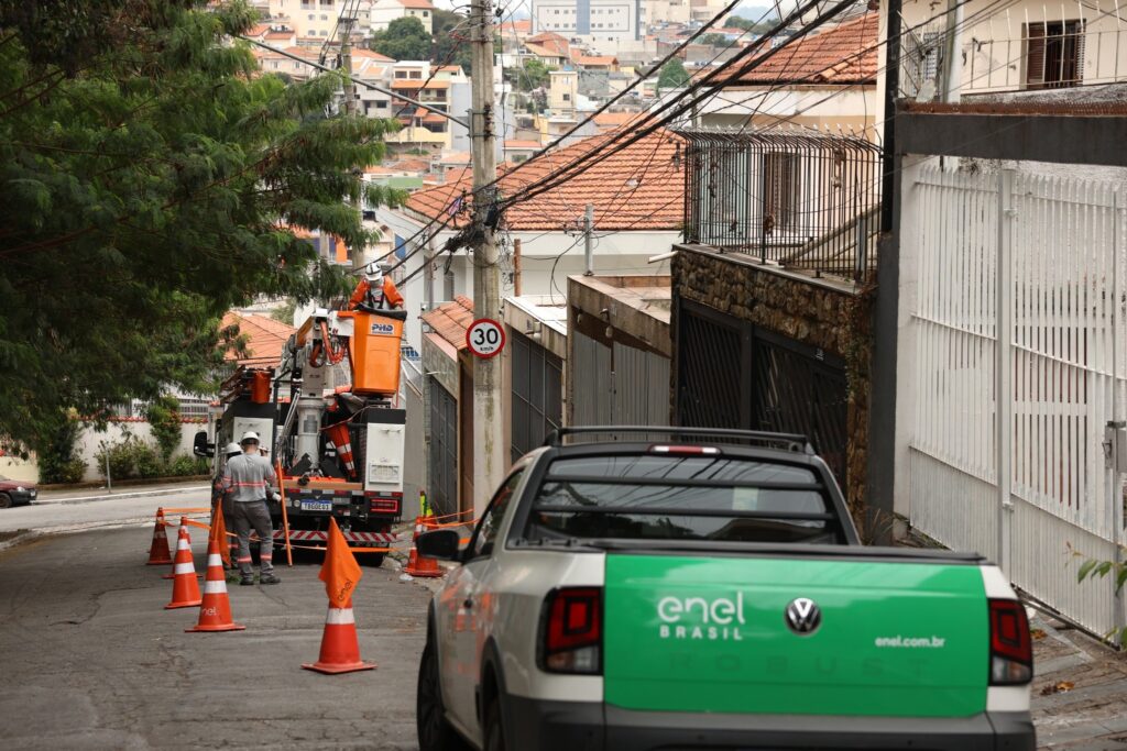 multa Enel Procon: Trabalhadores realizam manutenção na rede elétrica em rua residencial de São Paulo.