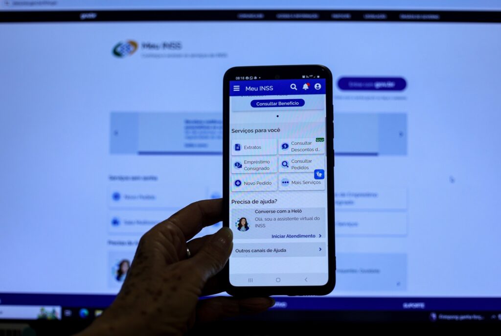 BPC: mão de idoso utilizando o aplicativo Meu INSS em um smartphone para consultar benefícios.