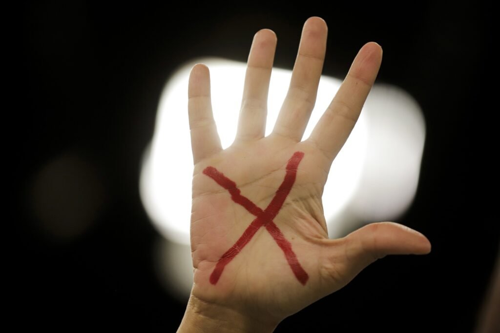segurança das mulheres: mão aberta com a palma voltada para frente e um X vermelho pintado no centro.
