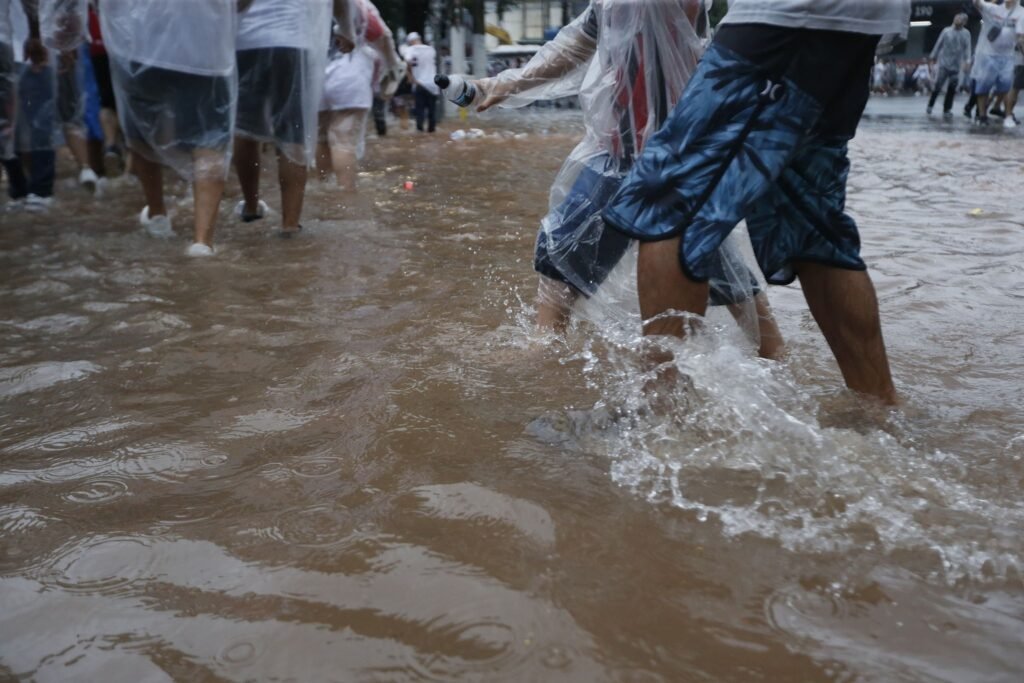 alagamentos em São Paulo: pessoas caminham por rua alagada com água barrenta.