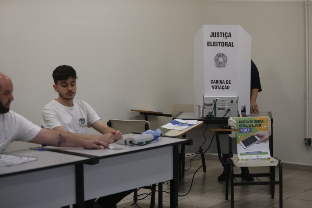 prorrogação do horário de votação: cabina de votação e urna eletrônica em seção eleitoral.