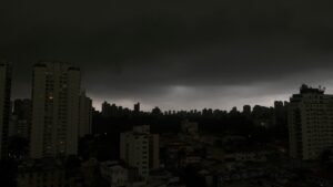 Previsão de chuvas: cidade sob céu escuro e nublado, sugerindo temporal com prédios sob nuvens densas.