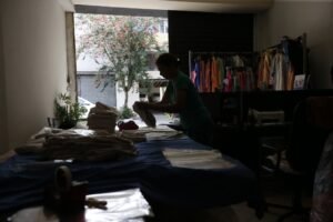 previsão do PIB: mulher trabalha em oficina de costura com pouca luz