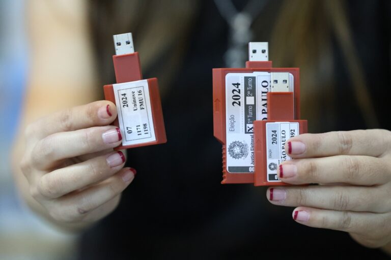 Cadu de Lula: Mãos seguram mídias de USB da Justiça Eleitoral para votação.