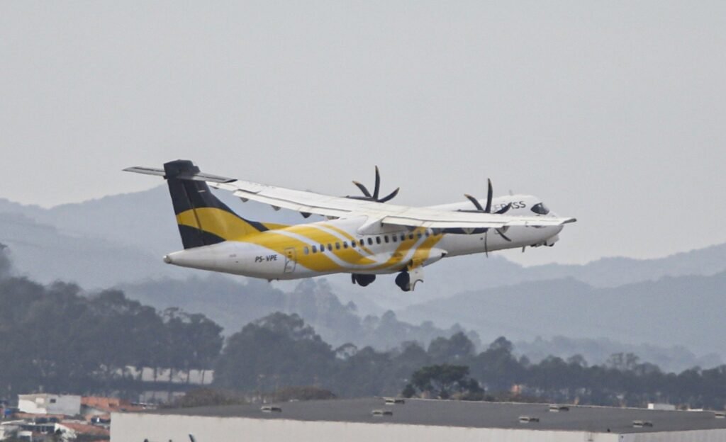 queda de avião da Voepass: Avião da Voepass, branco com listras amarelas, decolando em frente a colinas arborizadas.