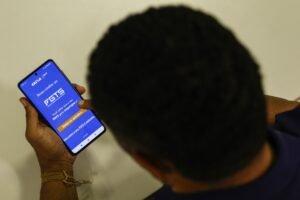 orçamento do FGTS: homem segura smartphone com aplicativo do FGTS aberto.