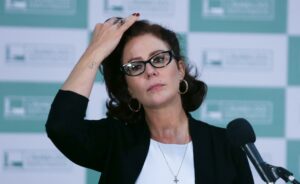 Deputada Carla Zambelli com a mão na testa durante coletiva de imprensa.