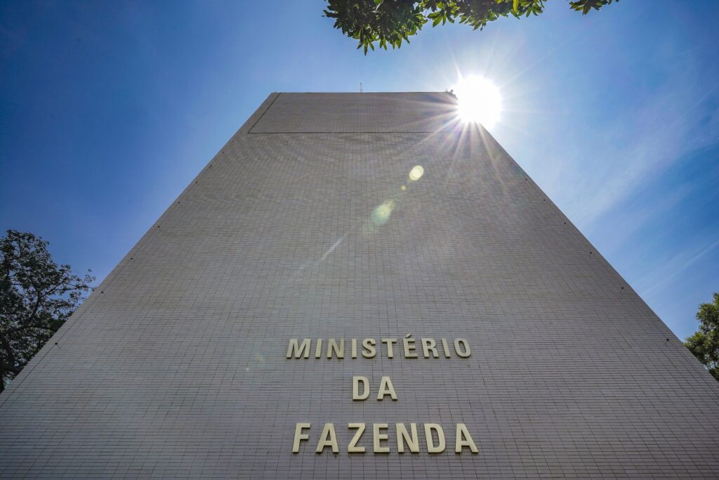 arrecadação federal: Vista em ângulo baixo da fachada do prédio do Ministério da Fazenda sob um céu azul.