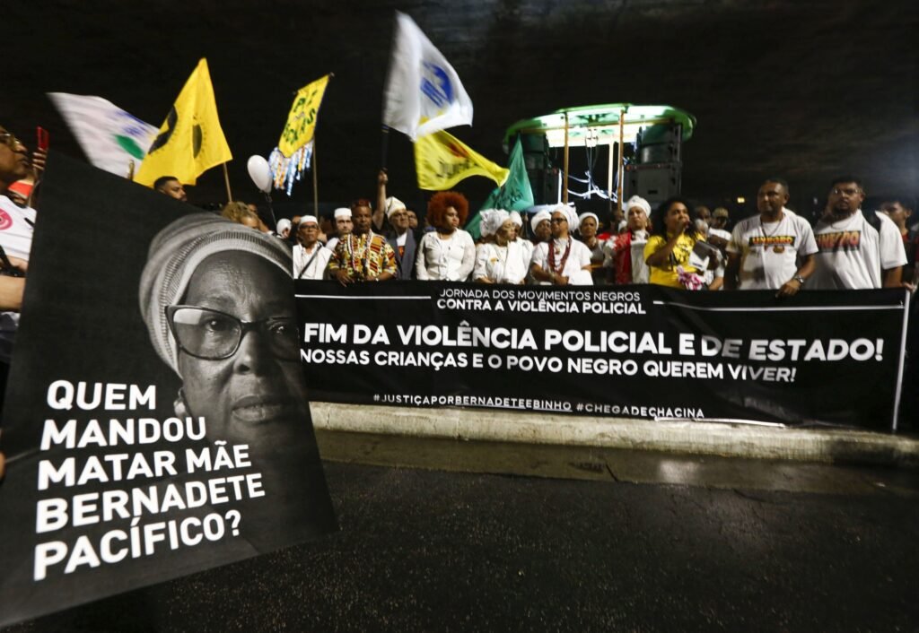 assassinato de Mãe Bernadete: manifestantes seguram faixa e cartaz com a foto da líder quilombola durante protesto.
