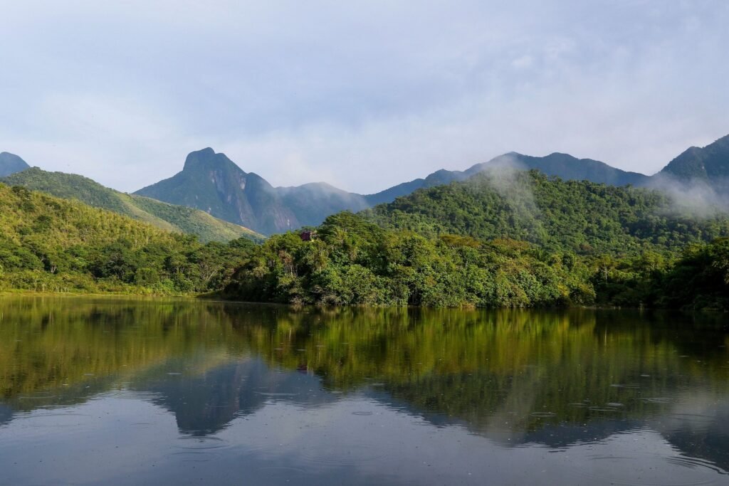 reserva ambiental: Montanhas cobertas por floresta densa refletidas em um lago calmo na Região Serrana do Rio de Janeiro.