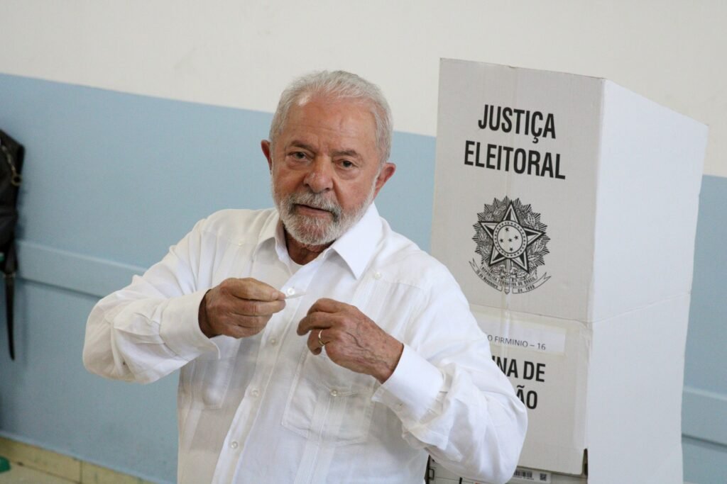 agenda dos presidenciáveis: Luiz Inácio Lula da Silva segura comprovante de votação ao lado de urna da Justiça Eleitoral.