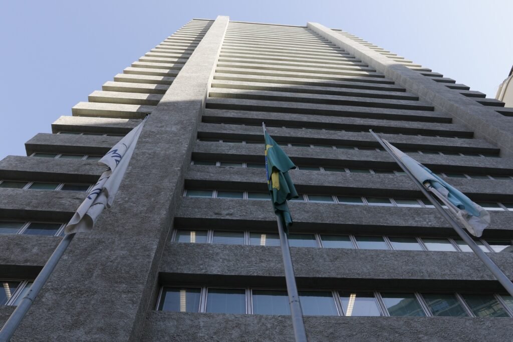 India Armelau: fachada do edifício da Alerj vista de baixo, com a bandeira do Brasil hasteada.