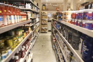 Corredor de supermercado com prateleiras de condimentos e alimentos para ilustrar o consumo de alimentos.