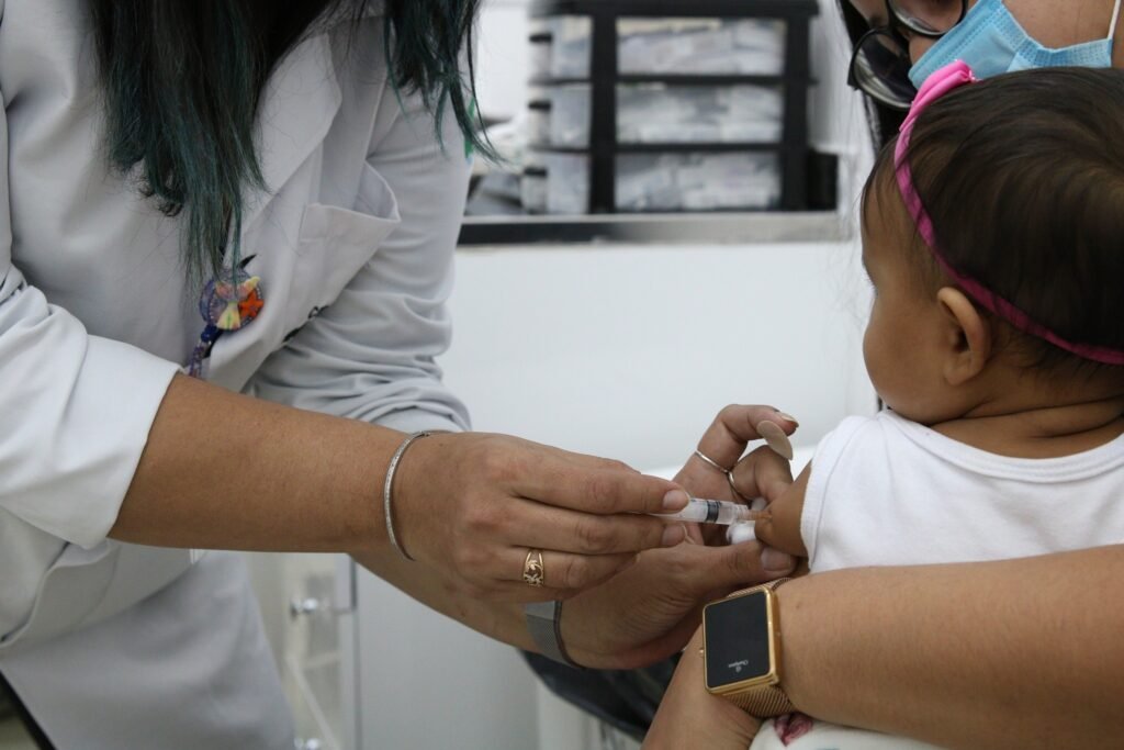 internações por quedas: profissional de saúde aplica vacina no braço de um bebê em unidade de saúde do SUS.