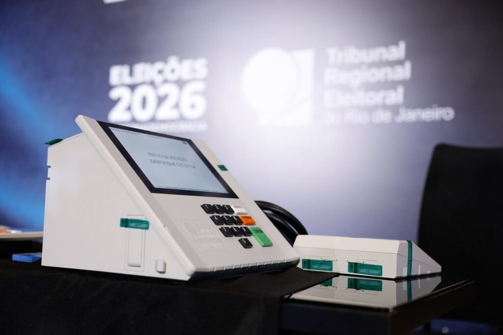 local de votacao: Urna eletrônica brasileira diante de painel do Tribunal Regional Eleitoral do Rio de Janeiro.