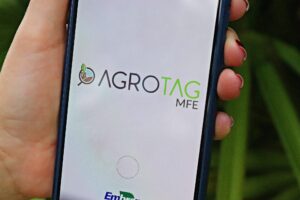 efeito estufa: Mão segurando smartphone com o logotipo Agrotag MFE da Embrapa.
