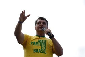 fuga de Flávio Bolsonaro: Homem com camiseta amarela com a frase "MEU PARTIDO É O BRASIL" fala ao microfone.