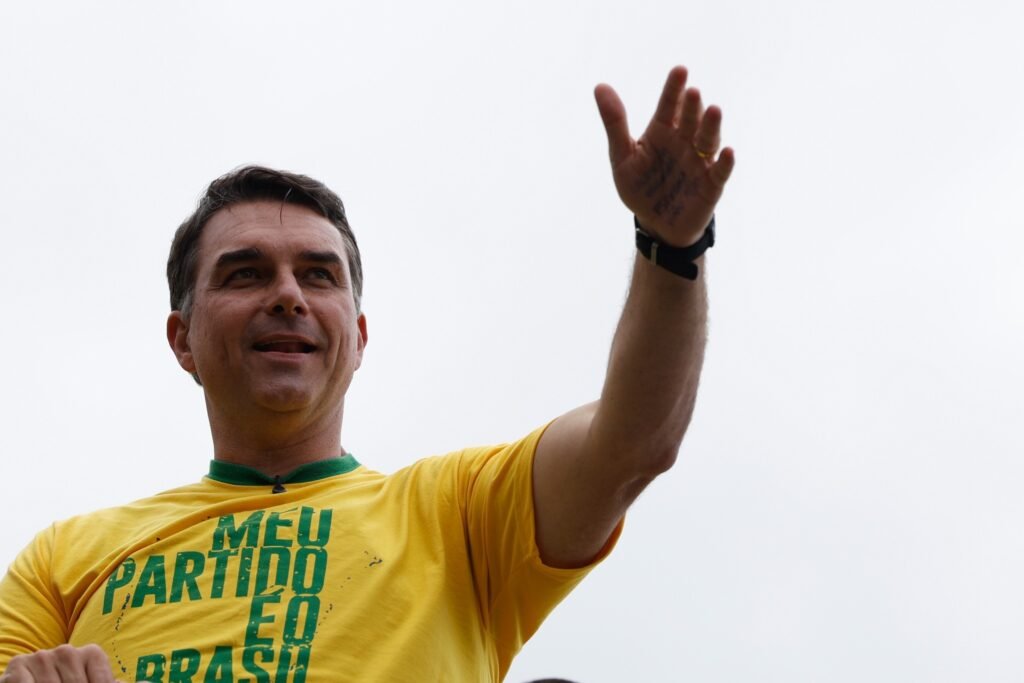 agenda dos presidenciáveis: Flávio Bolsonaro acena vestindo camiseta amarela.