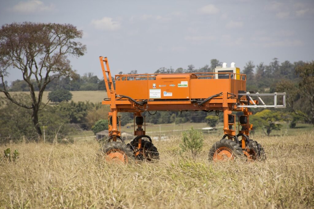 aporte para inovação: Robô agrícola móvel laranja com a inscrição 'Robô agrícola móvel' posicionado em campo de vegetação seca.