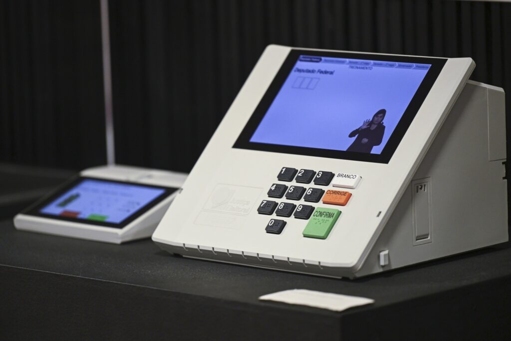 Urna eletrônica em exposição no Museu do Voto do TSE, com tela exibindo instruções de votação.