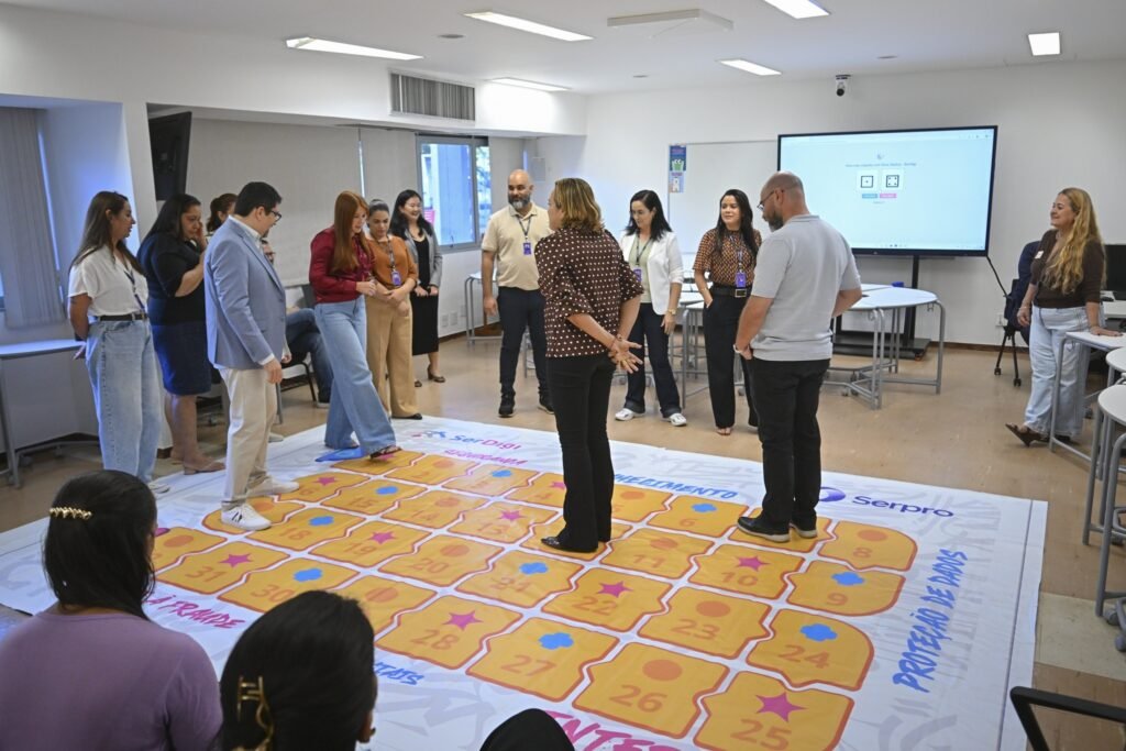 cursos gratuitos para professores: Grupo de pessoas em torno de um tapete educativo com a frase proteção de dados.