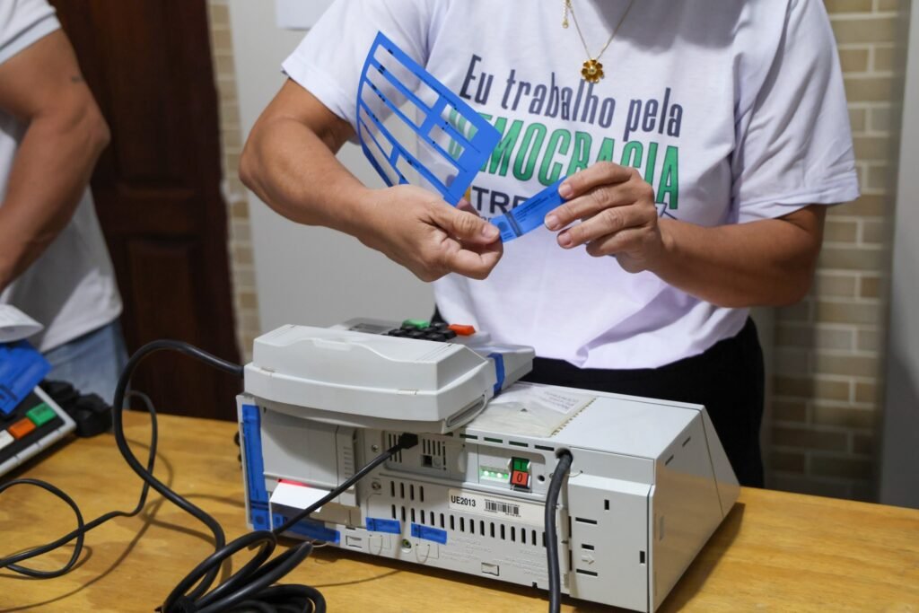 segundo turno das eleições: pessoa manuseia lacres de segurança em urna eletrônica