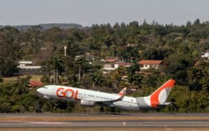 fuga de Flávio Bolsonaro: Avião de passageiros da GOL decola em aeroporto com vegetação ao fundo.