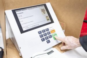 censura nas redes: Mão de pessoa anônima pressiona o botão confirma no teclado de uma urna eletrônica.